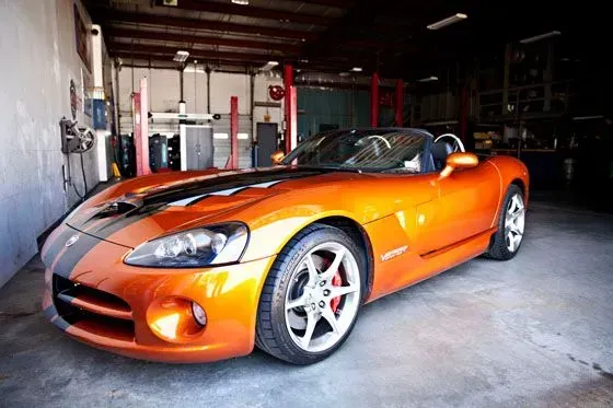 Orange sports car with black racing stripes parked in a garage | Sparks Tire & Auto