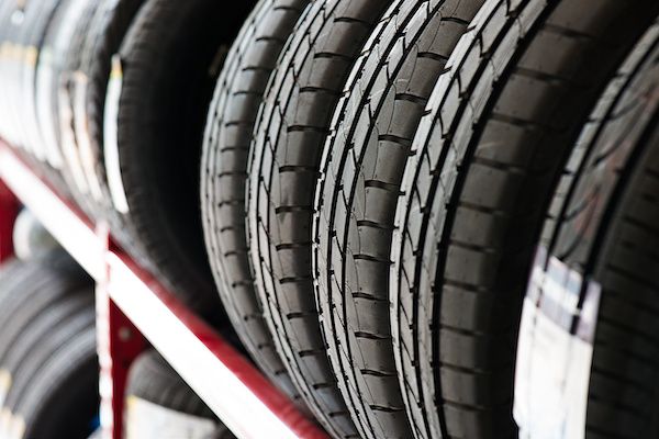 Rows of black tires stacked on metal racks in a store or warehouse | Sparks Tire & Auto