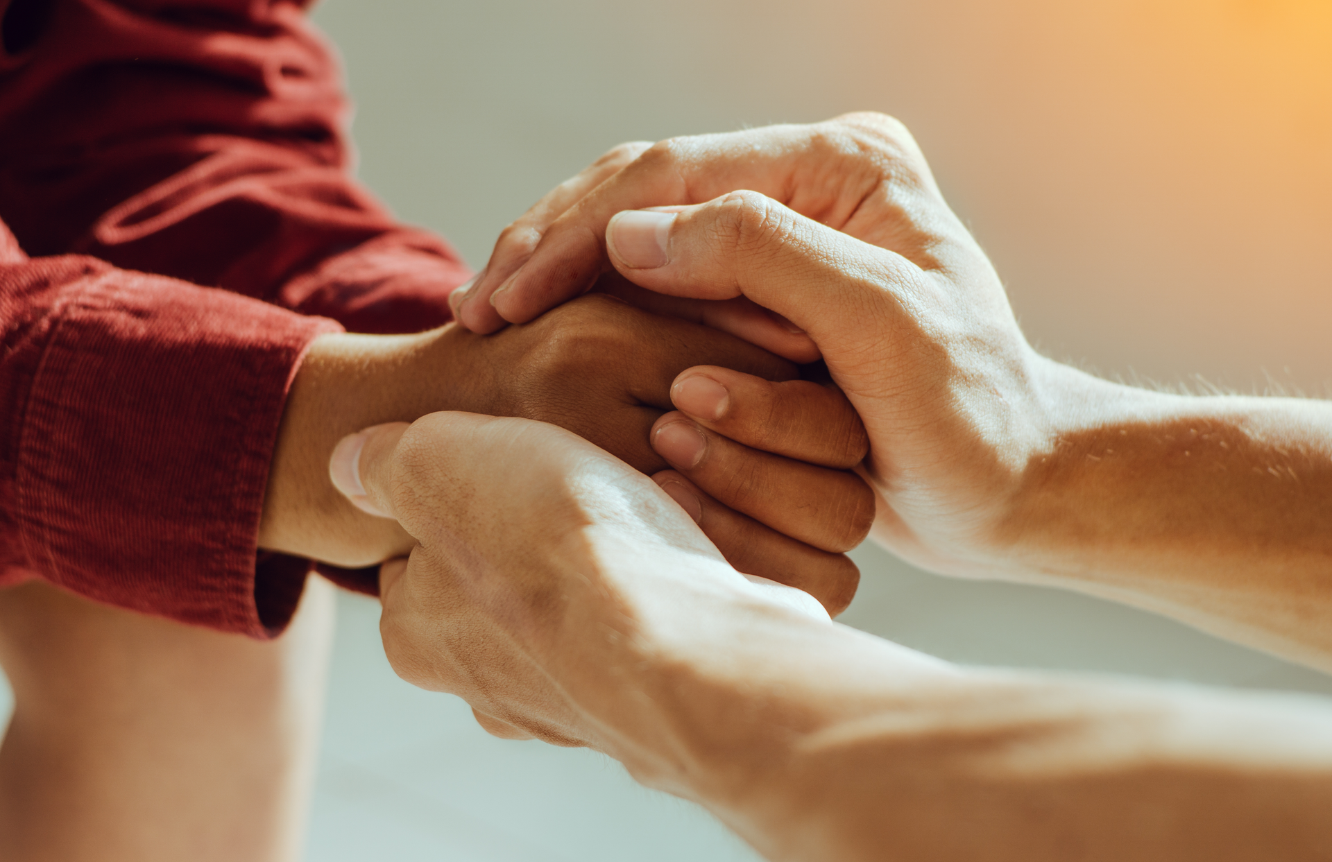 Hands clasped, one person offering support and comfort to another.