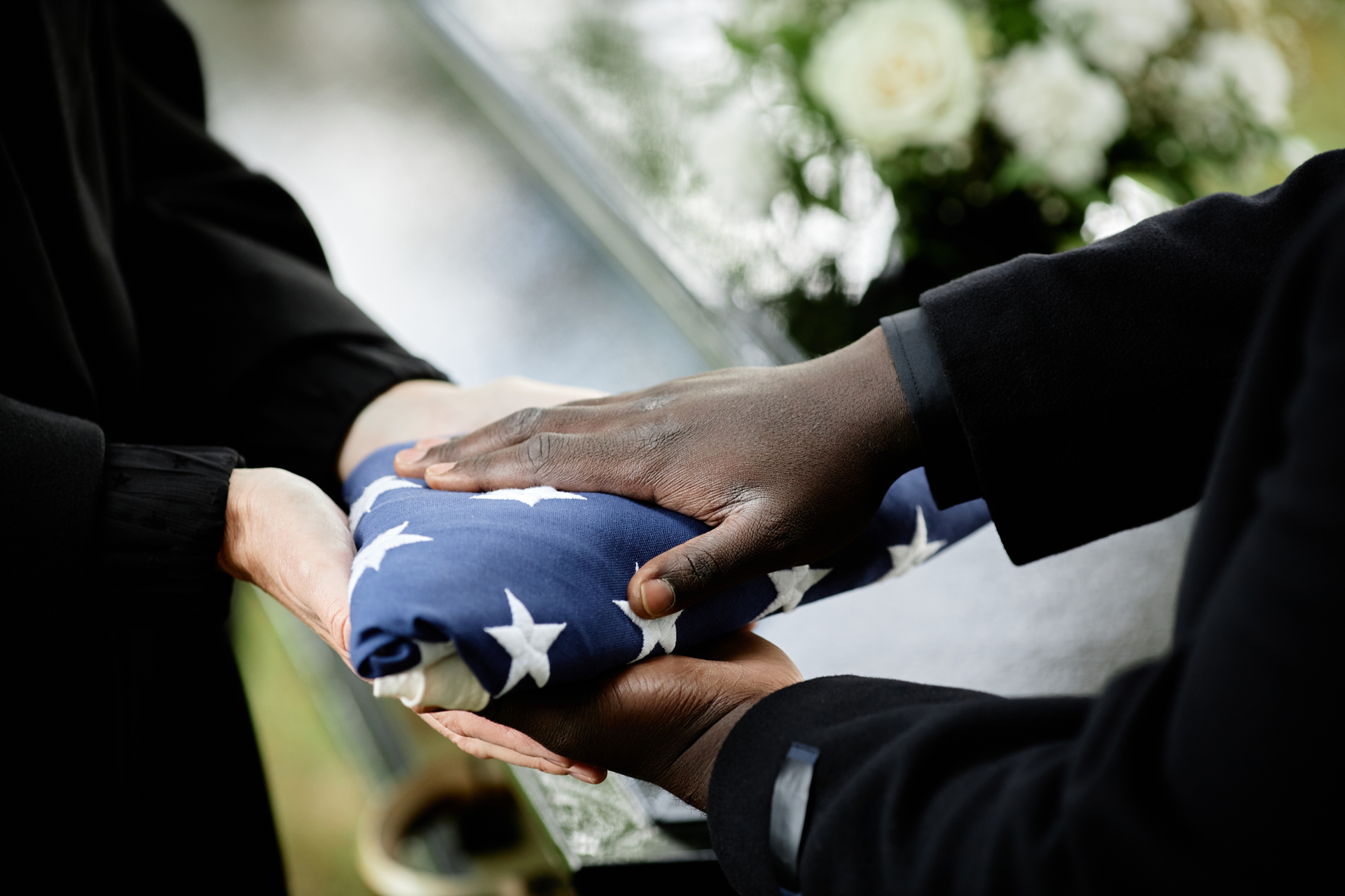 A man in a military uniform is holding an American flag in his hands.