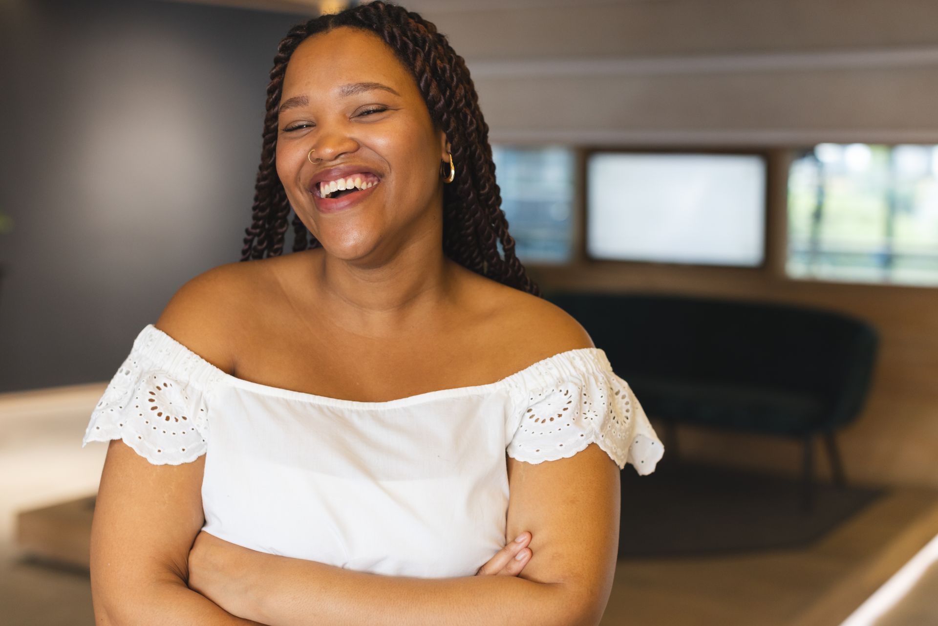 A woman is sitting at a table with her hand on her chin and smiling.