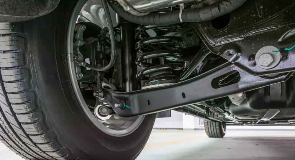 A close up of the underside of a car with a tire and shock absorber. — Budget Tyre Shed In Charmhaven, NSW