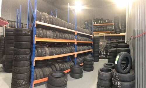 A few shelves storing a lot of tyres with stacks on the floor — Budget Tyre Shed In Charmhaven, NSW