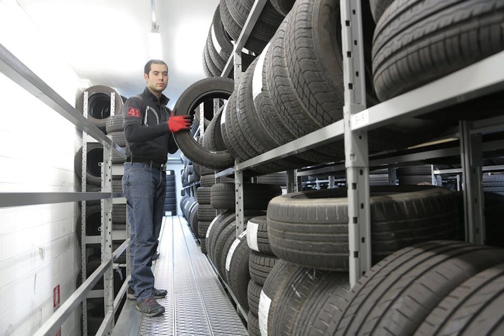 Budget Tyre Shed employee holding a black tyre at the Charmhaven workshop, providing quality tyre services for Central Coast customers