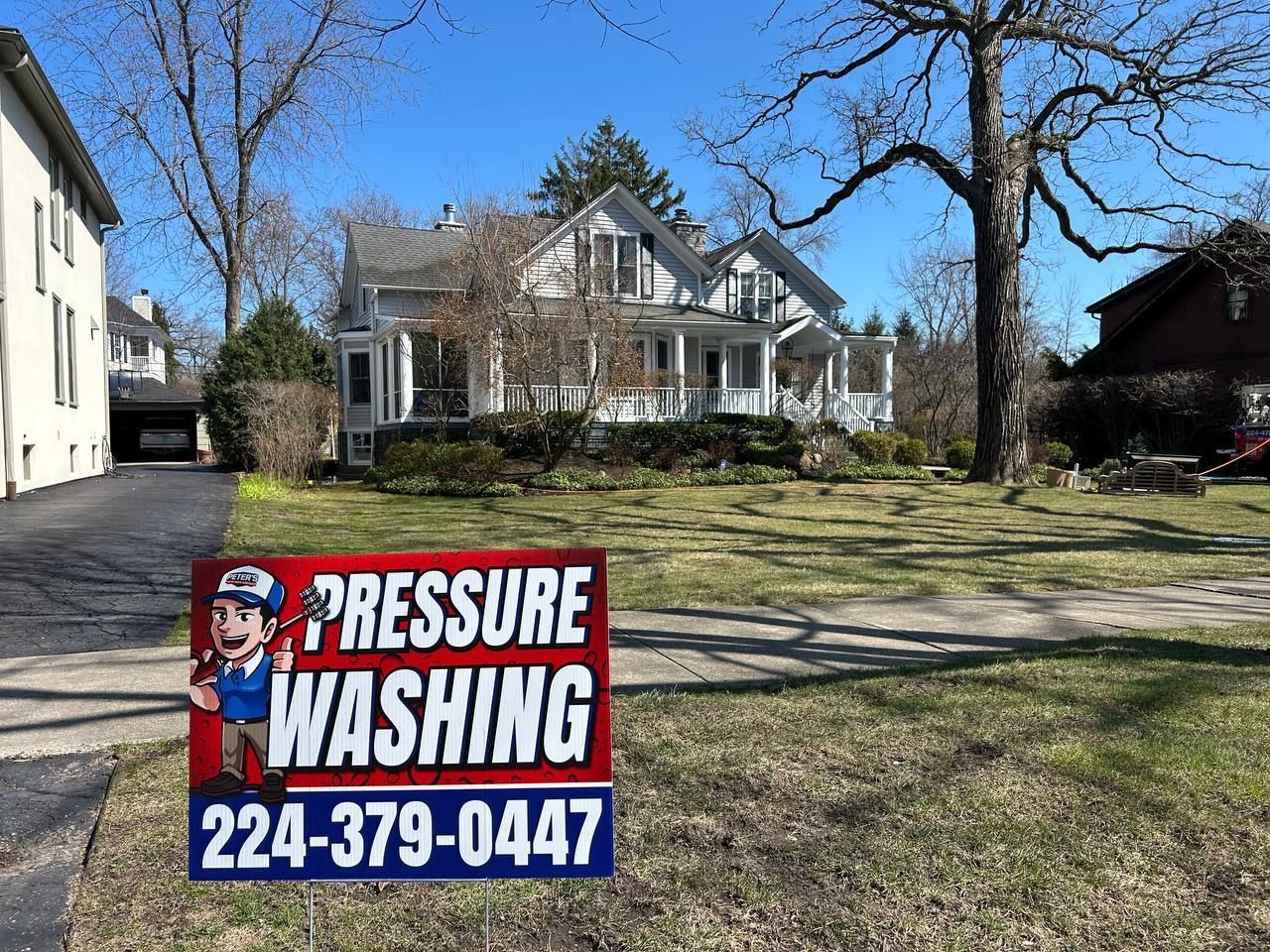 Image of a Peter Power Washing yard sign displayed during an HOA Power Washing service, placed on a residential lawn in front of suburban homes and trees.
