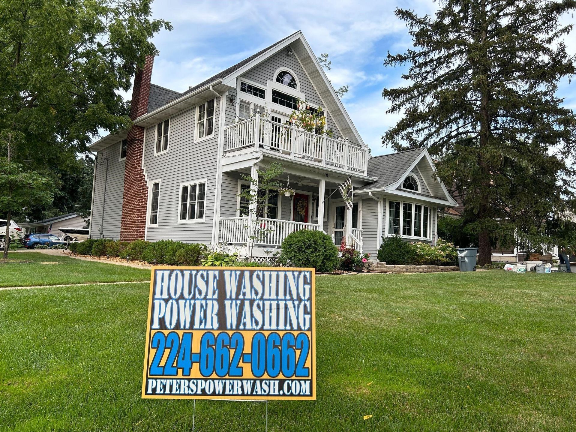 You can see an image of a large suburban home during a Soft Washing power washing service in Chicagoland, featuring a Peter Power Washing sign placed on the lawn in front of the freshly cleaned property.