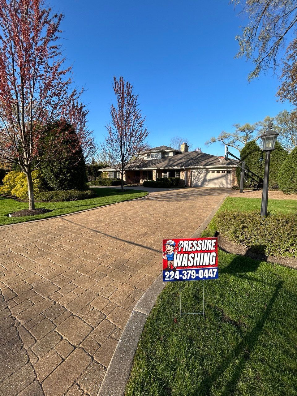 Picture of a residential property during a Soft Washing House Washing service, showing a large home surrounded by colorful trees, a green lawn, and a bright blue sky in a quiet suburban neighborhood.