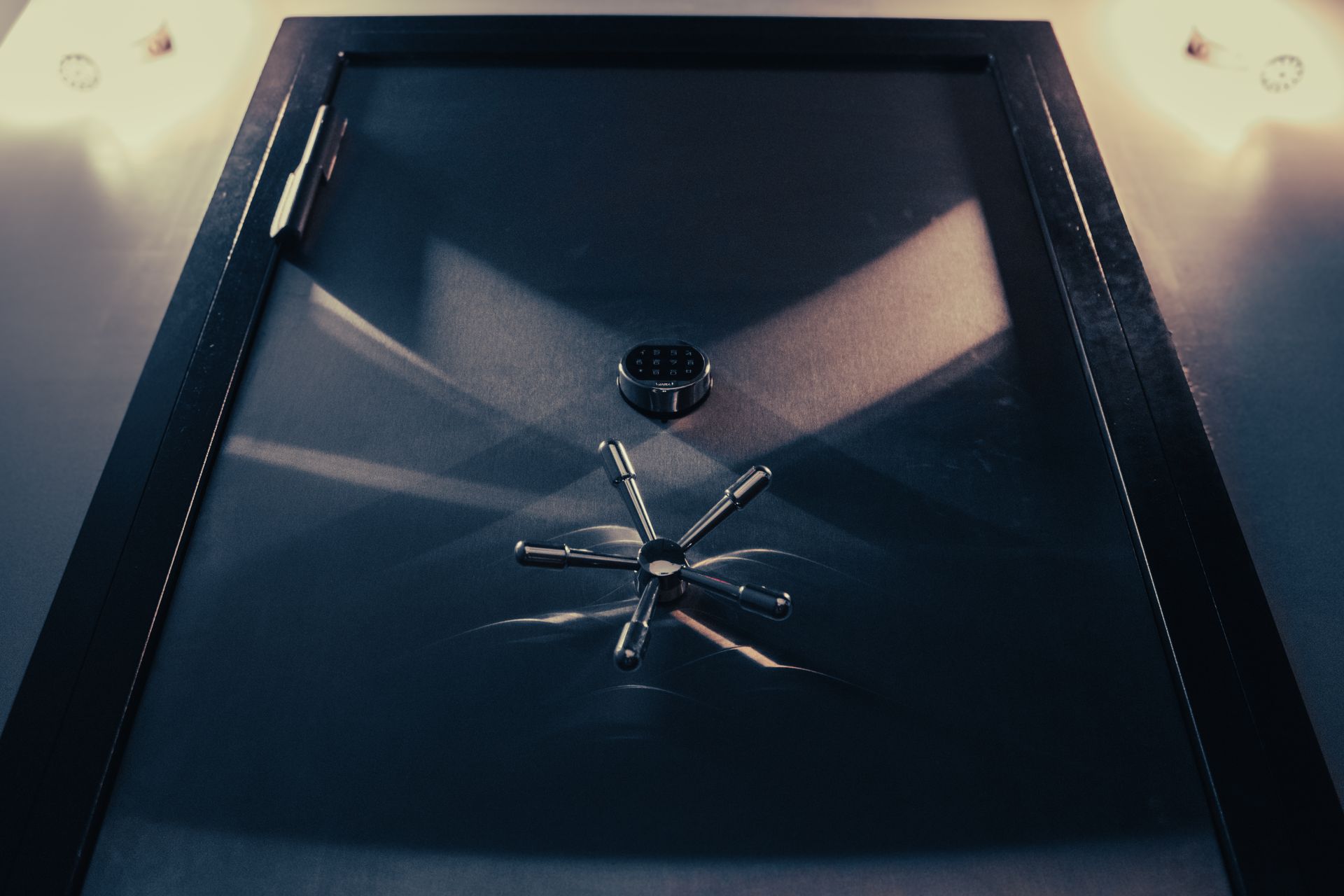 Open black safe door with metallic wheel lock, viewed from above.