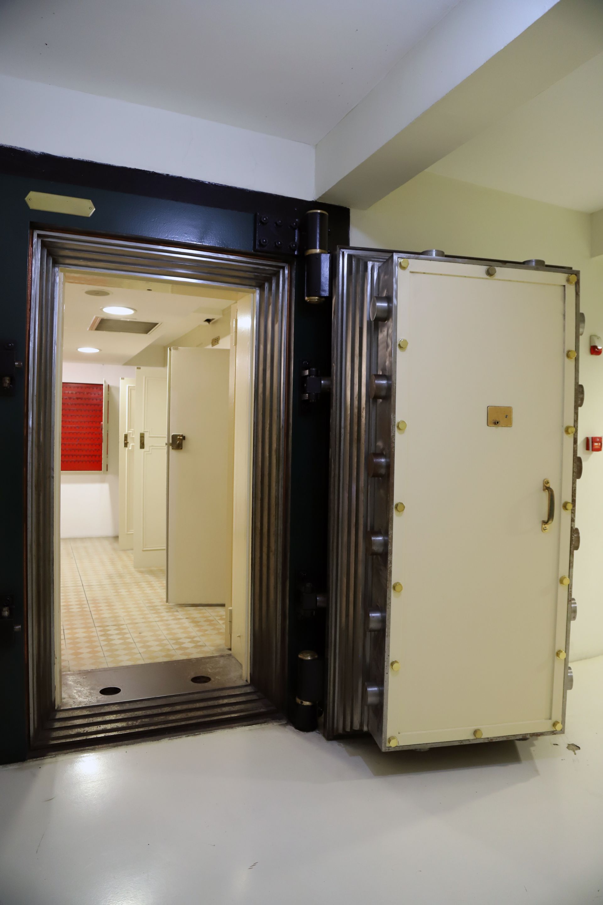 Open vault door in a secure hallway, showing a lit interior room beyond.