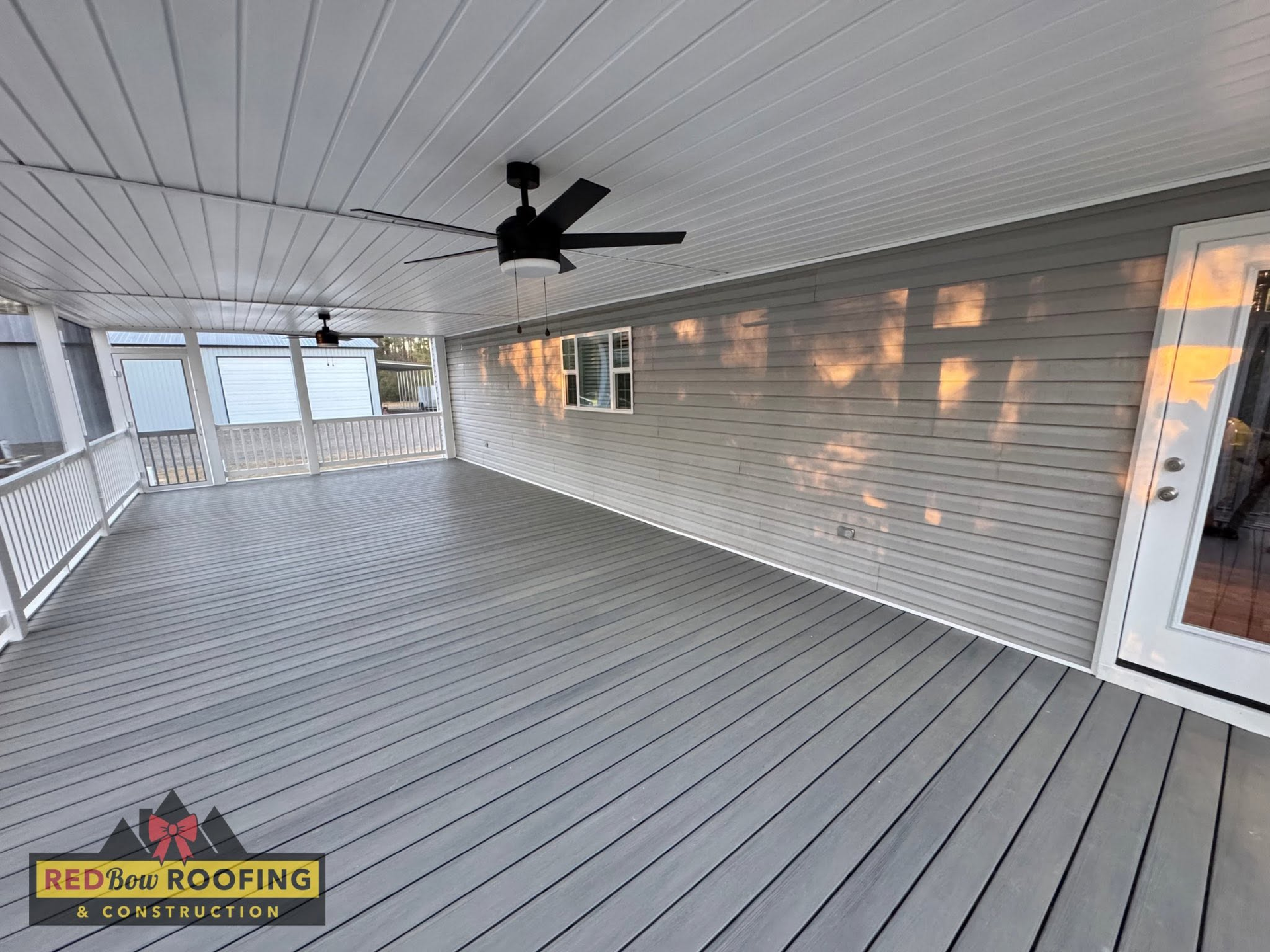 Covered porch with gray flooring, white siding, ceiling fan, and sliding glass door.