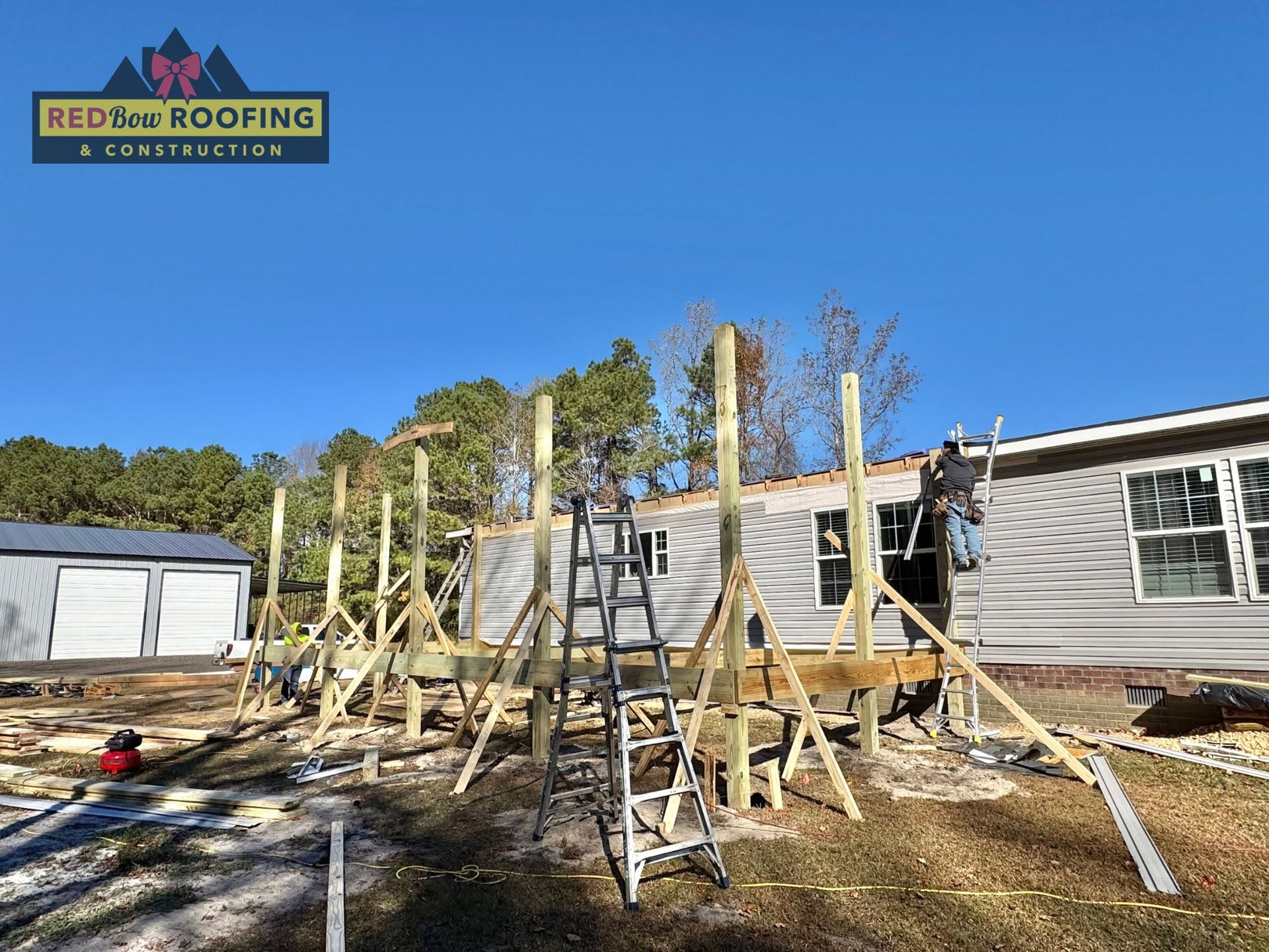 Roofing crew working on a house roof under construction with ladders and scaffolding outside.