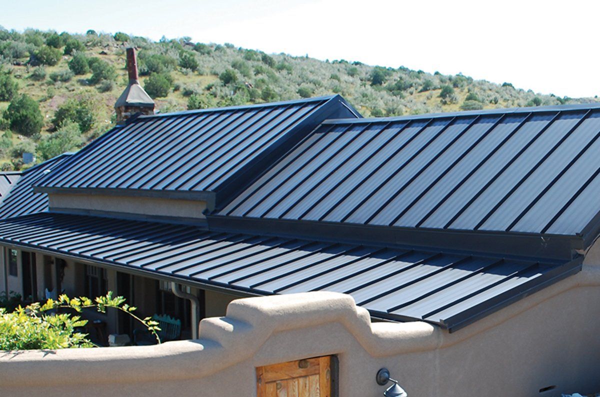 Slate-roofed house with a chimney, viewed from a balcony, with green hills in the background