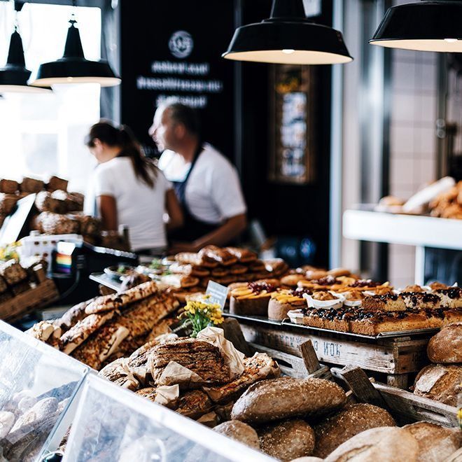 Bakery display of bread and pastries; two people behind counter.