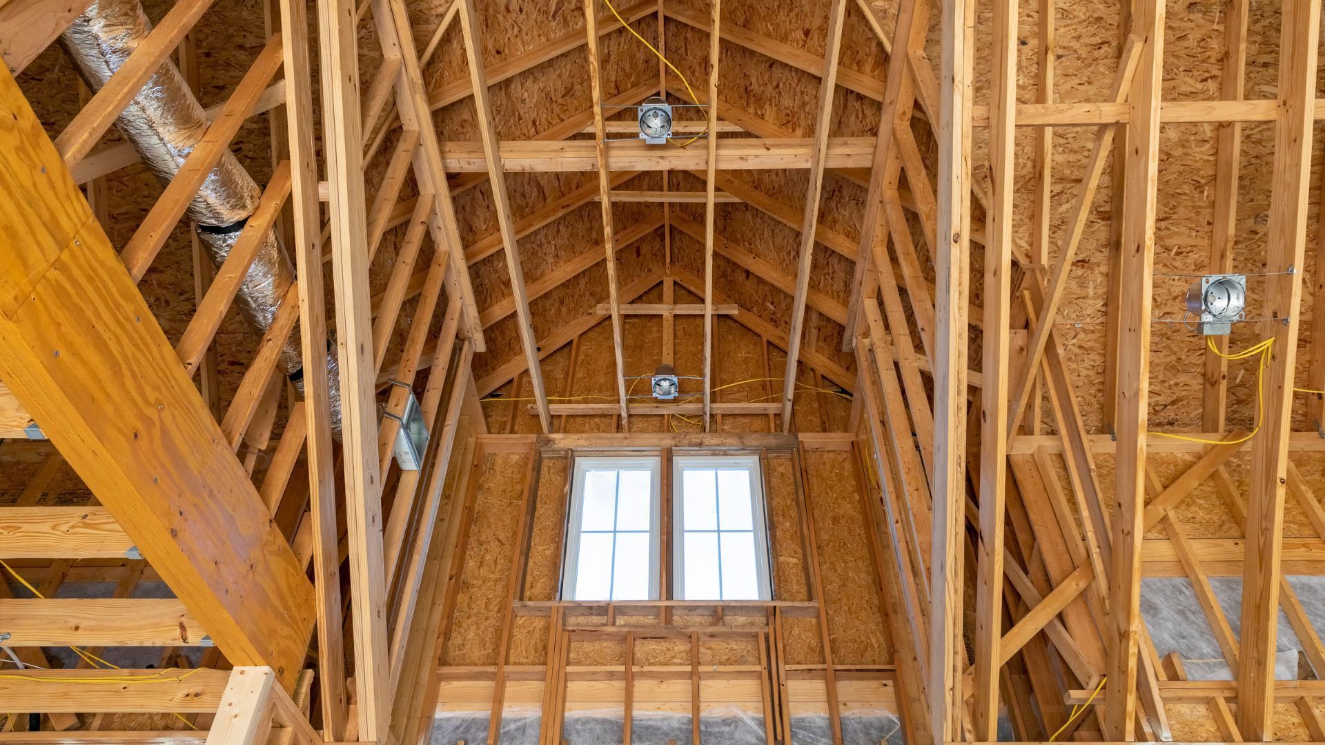 Interior of aattic with exposed walls and roof framing before spray foam insulation installation.