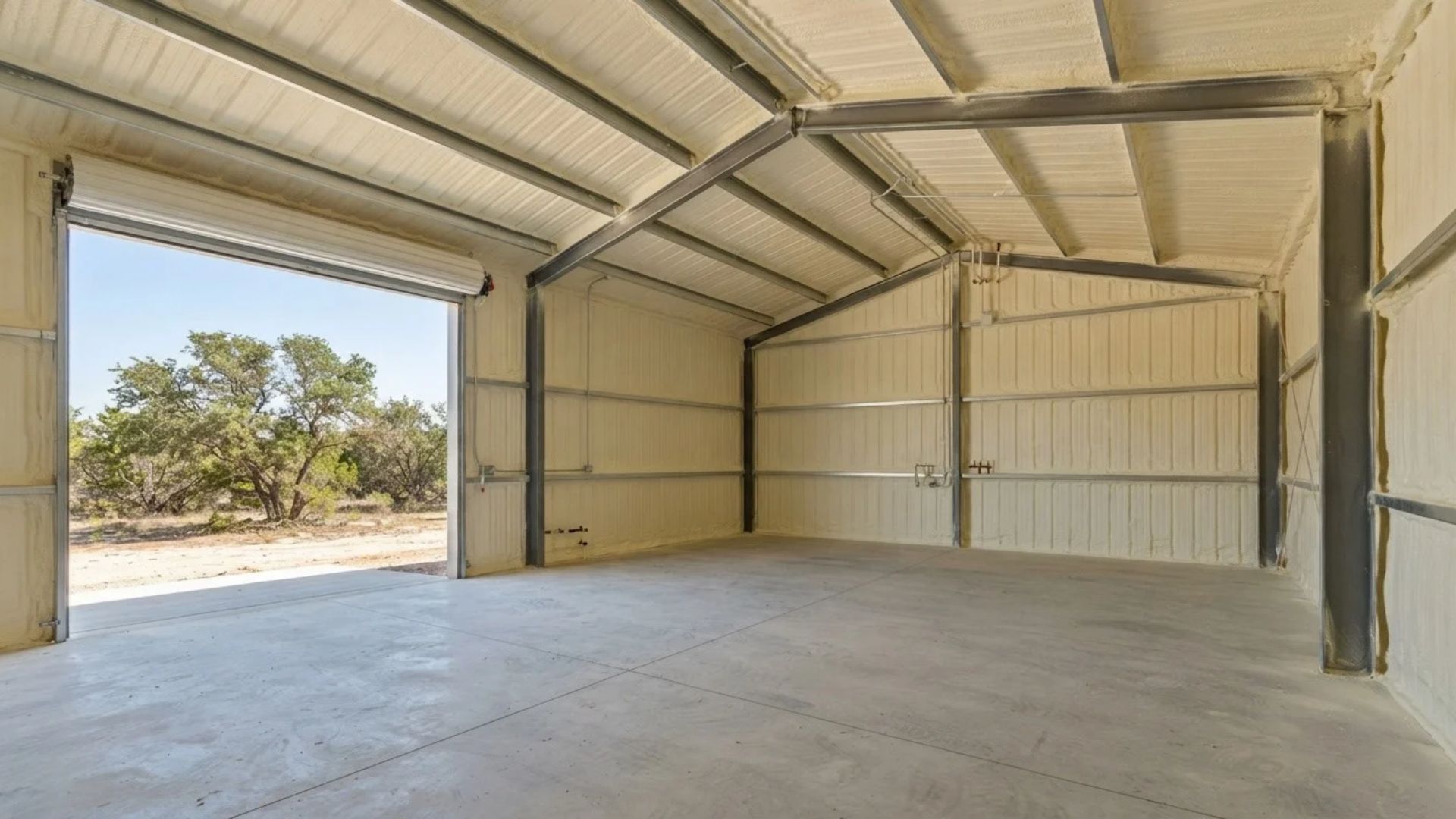 Finished spray foam insulation covering the underside of a metal building roof, with consistent foam coverage between steel beams and roof supports in Tyler, Texas.
