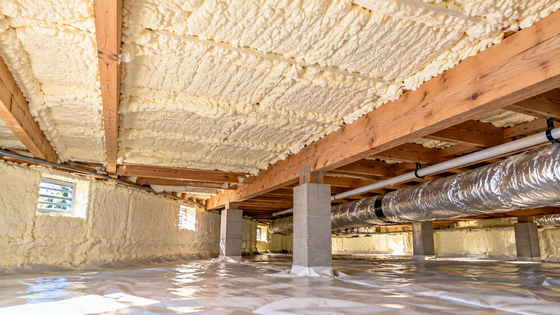 Completed crawl space spray foam insulation in Tyler, Texas, featuring insulated floor joists, foundation walls, HVAC ductwork, and a protective vapor barrier.