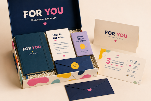 Open “FOR YOU” gift box with navy and cream cards and pink accents displayed on a white surface