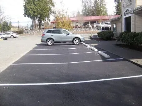 Empty parking lot with a silver SUV parked in an accessible space near a building.