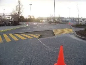 Empty parking lot with yellow road stripes, a speed bump, and an orange cone at sunset