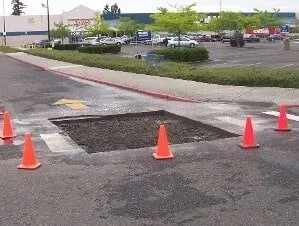 Orange cones around a patched pothole in a parking lot