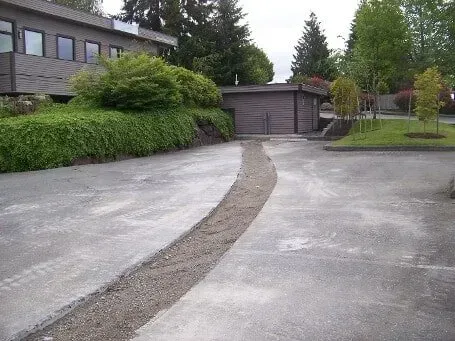 Curved paved driveway leading to a garage beside a building and hedges