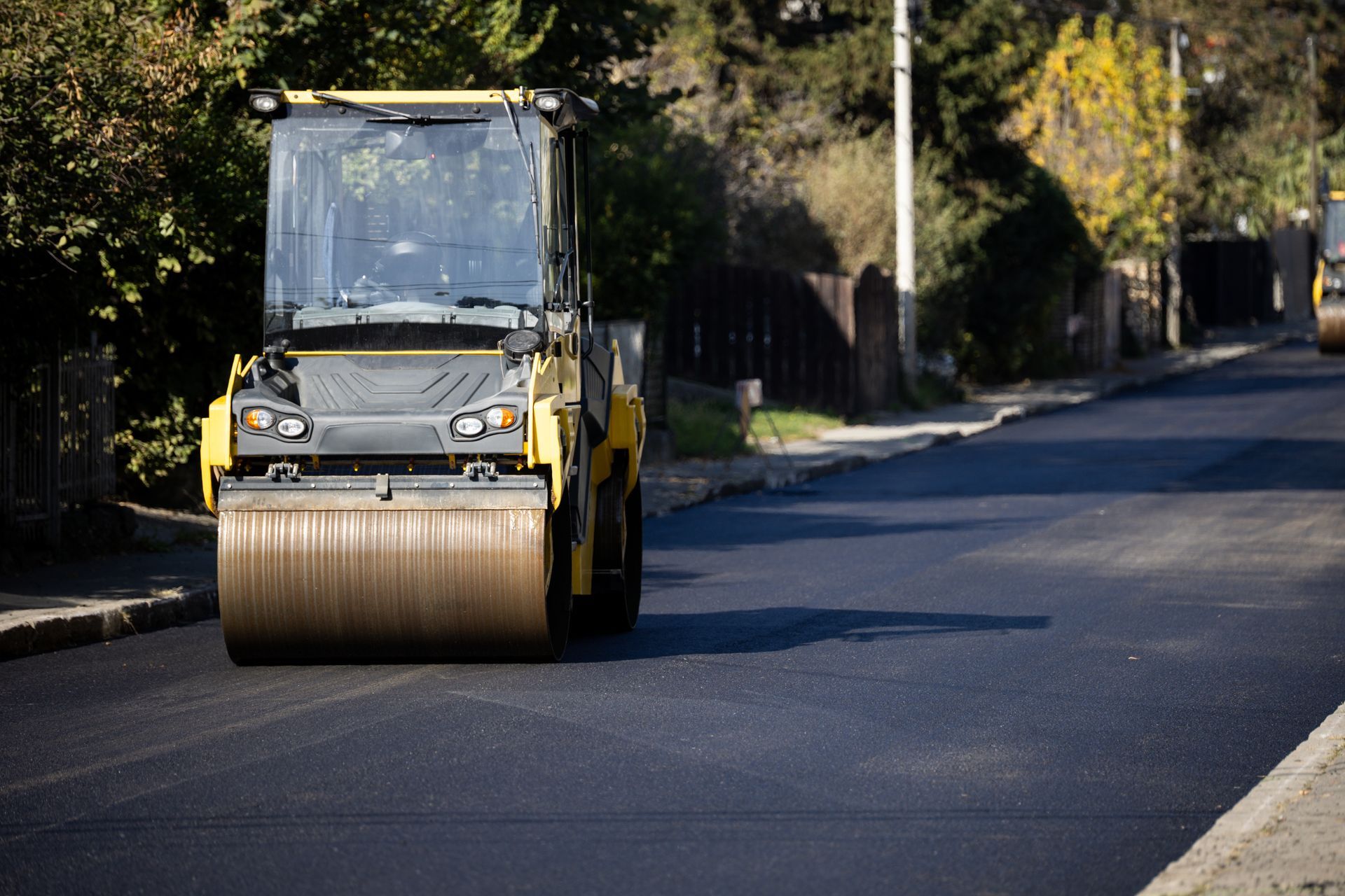 Road construction underway with steamroller compacting asphalt. Road construction underway with steamroller compacting asphalt.