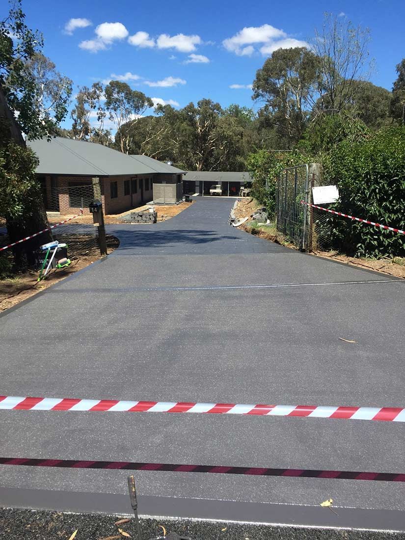 A Road With a Red and White Tape Along the Side of It and a House in the Background — Heritage Concrete In Uralla, NSW