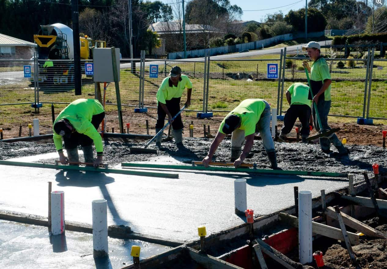 A Group Of Construction Workers Are Working On A Concrete Floor — Heritage Concrete In Uralla, NSW