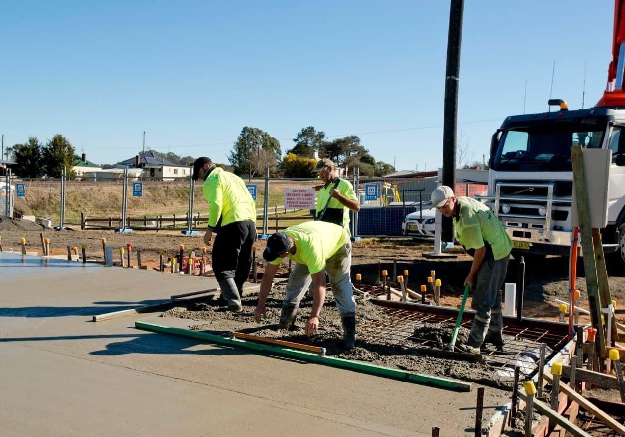A Group Of Construction Workers Are Working On A Concrete Surface — Heritage Concrete In Uralla, NSW