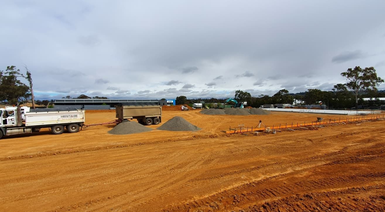 A Dump Truck Is Parked In The Middle Of A Dirt Field — Heritage Concrete In Uralla, NSW