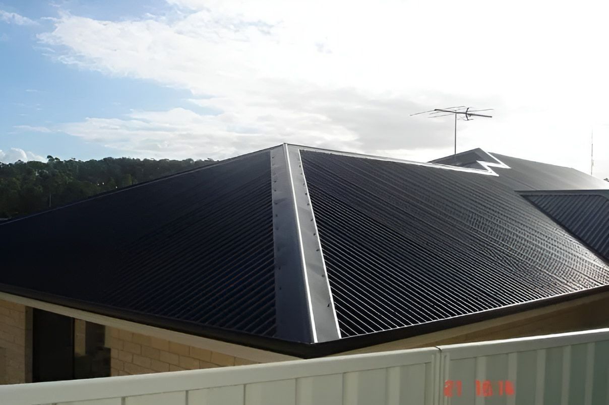 Black Corrugated Metal Roof on A House with A Light Blue Sky in The Background — Hi Tech Roofing in Port Stephens, NSW