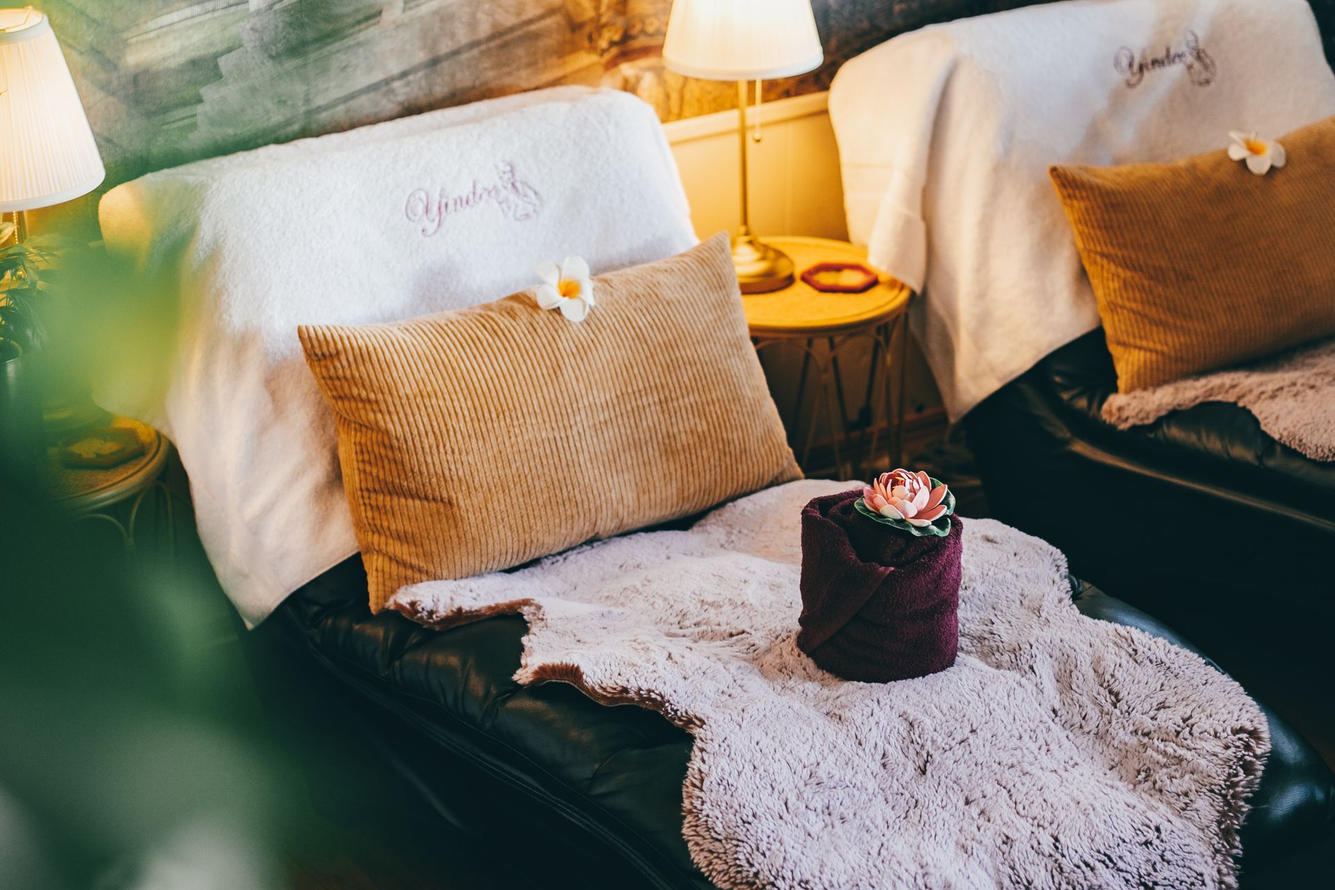 Cozy seating area with brown pillows, white blanket, and a small side table with a lamp.