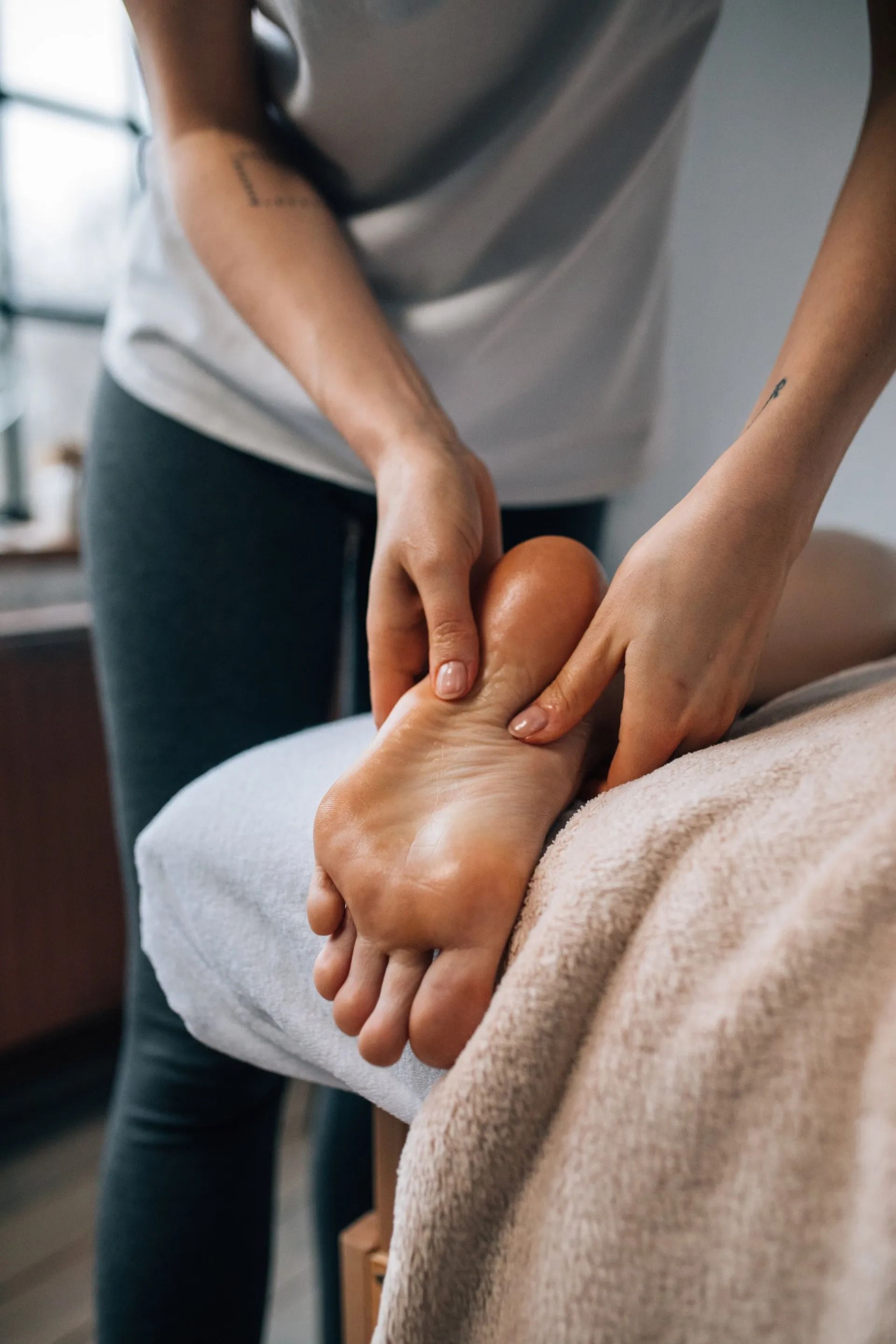 Person Giving Foot Massage. Hands Massaging a Foot on a Massage Table — Traditional Massage Services In Broadbeach, QLD