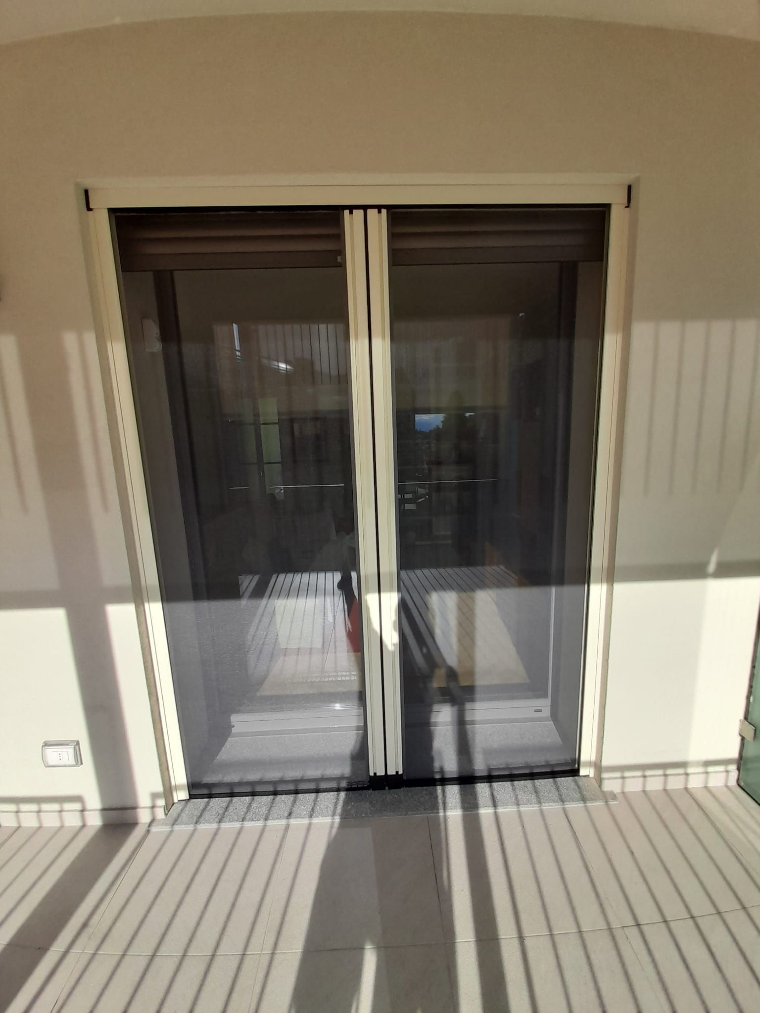 Porta a zanzariera doppia retrattile, telaio beige, rete nera.