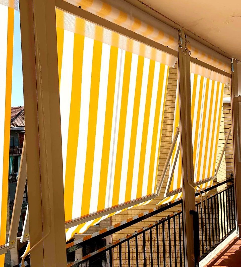 Tenda da sole a strisce gialle e bianche su un balcone, che fornisce ombra.