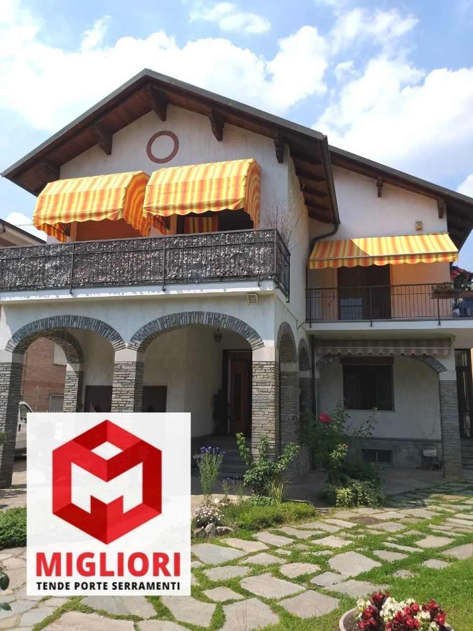 Casa a due piani con tende da sole a strisce gialle; logo