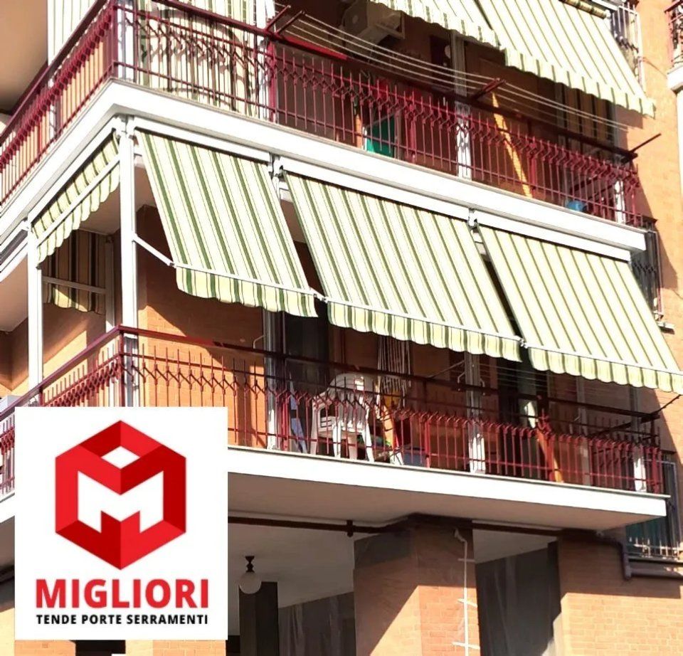 Balcone con tende a strisce, ringhiere rosse e logo