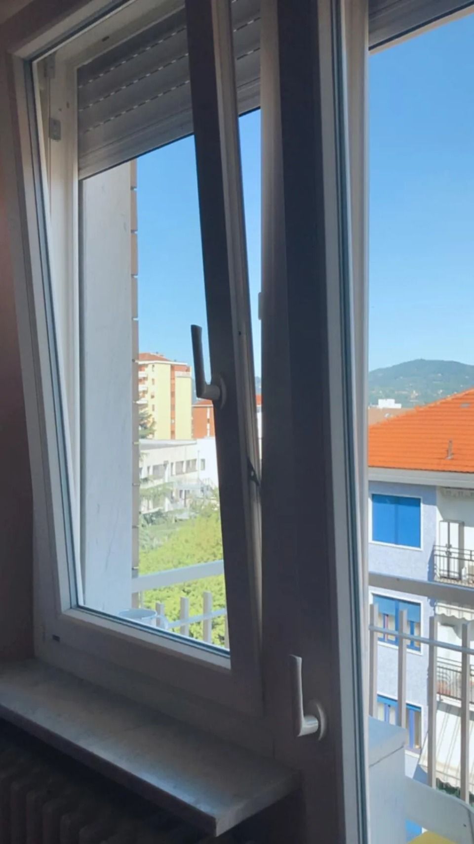 Finestra aperta con vista sul cielo azzurro, edificio all'esterno.