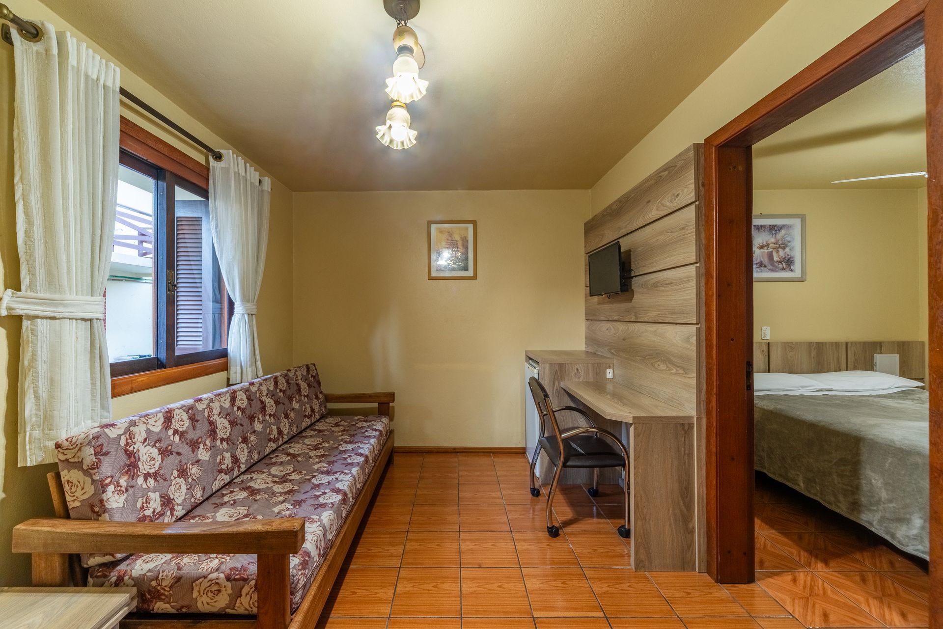 Um quarto de hotel com uma cama grande e uma geladeira pequena.