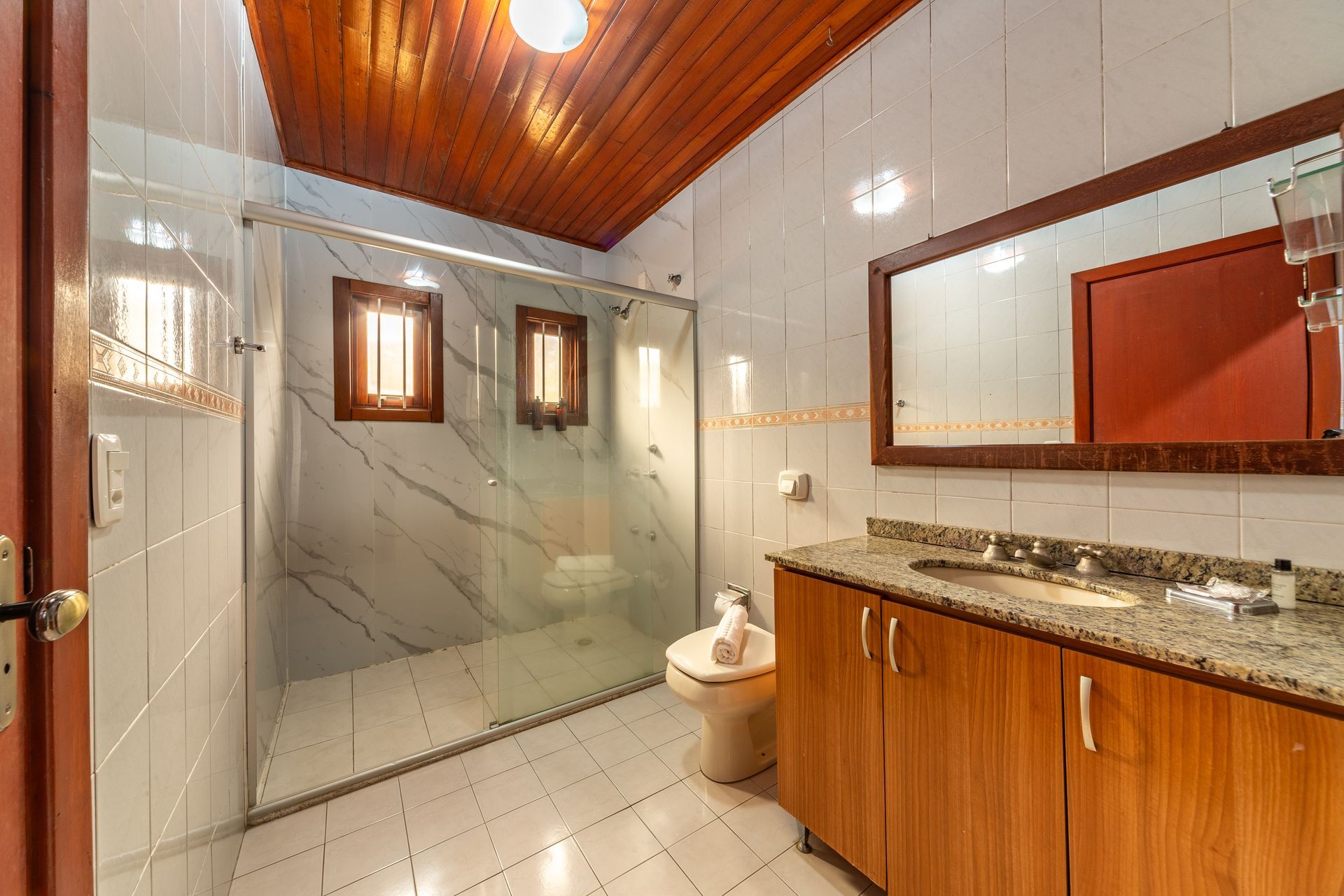 Uma sala com escrivaninha, cadeira, geladeira e televisão.