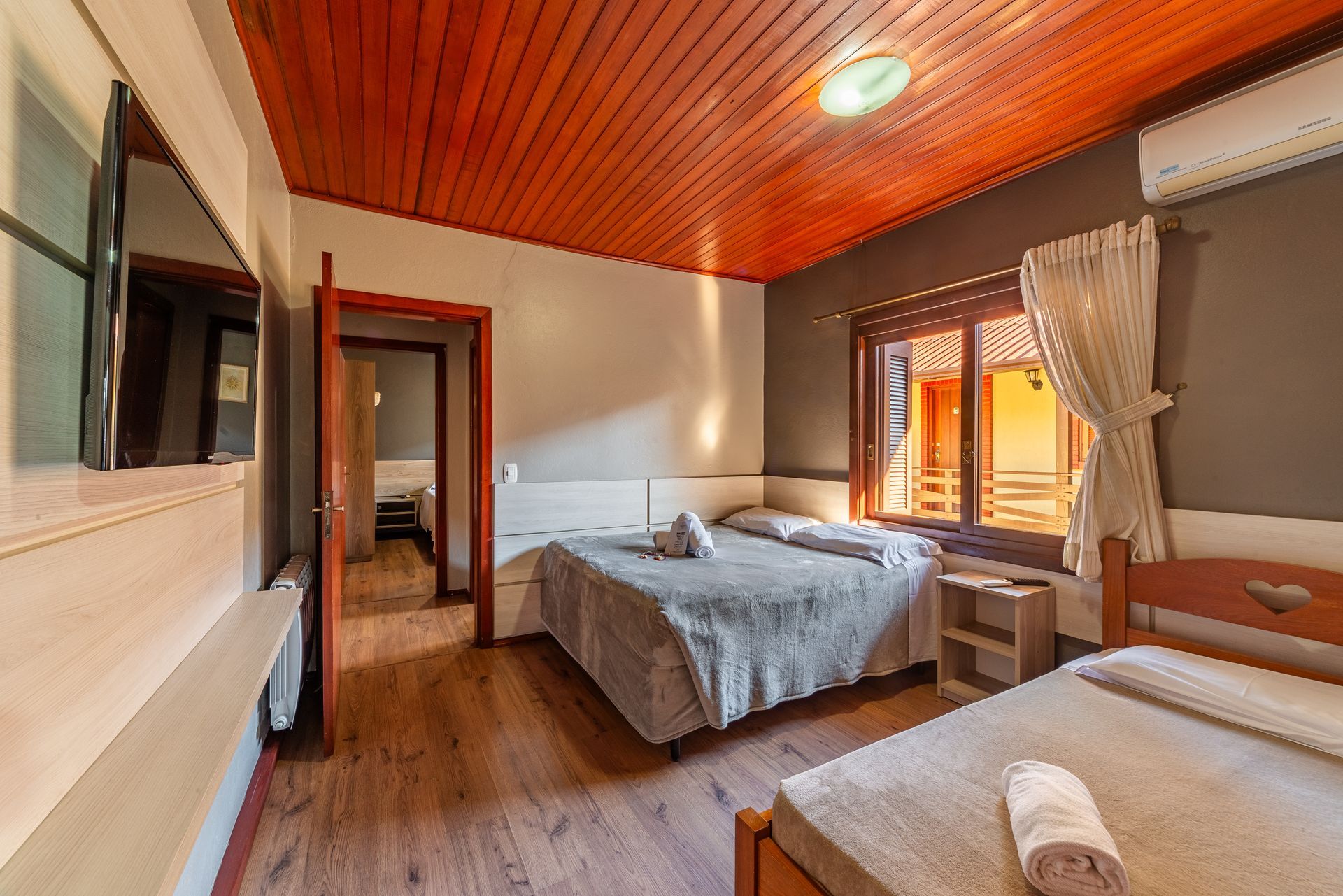 Um quarto de hotel com um sofá, mesa, cadeira e televisão.