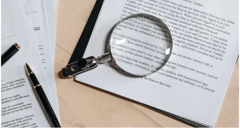 A magnifying glass laying on scattered papers