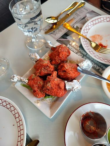 Chicken lollipops on a plate, served at a restaurant. Red-coated meat on foil-wrapped bones.