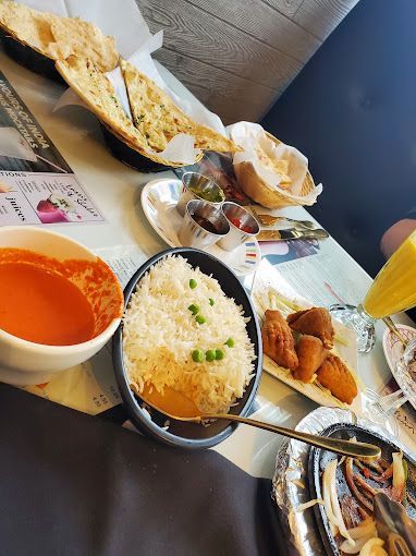 Overhead view of an Indian meal: rice, naan, soup, dips, and fried appetizers on a restaurant table.