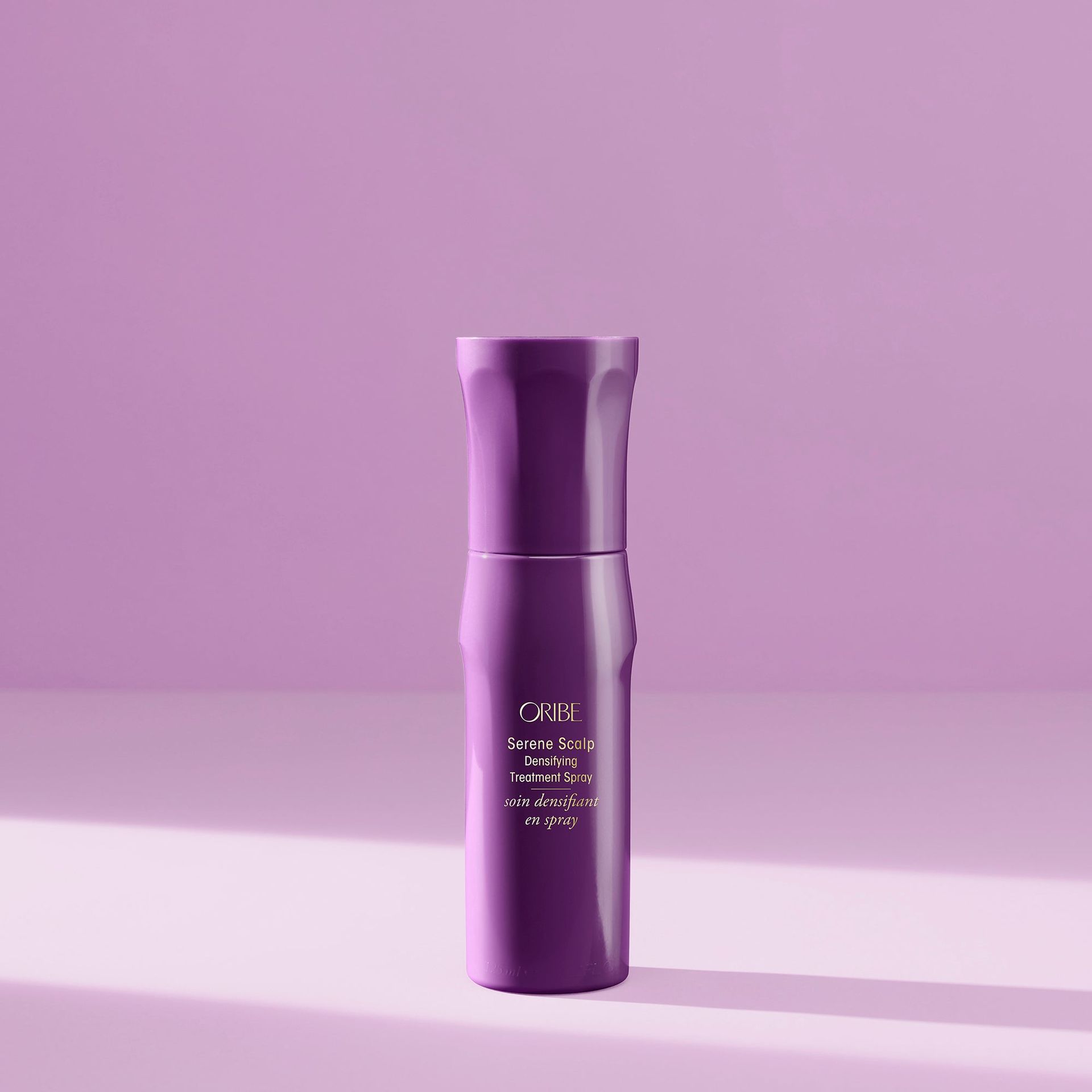 A purple, cylinder-shaped bottle with minimalist white text, set against a matching solid purple background.