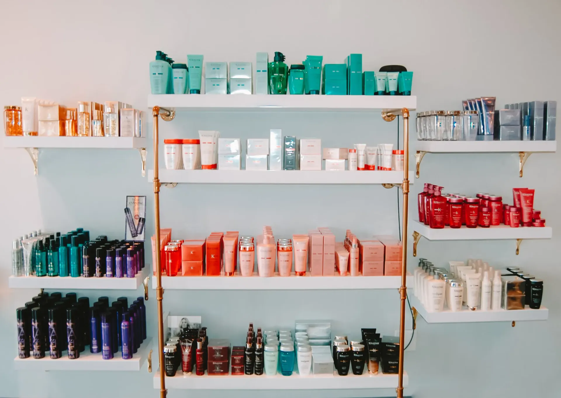 Shelves stocked with organized skincare and beauty products arranged by color in a brightly lit retail space.