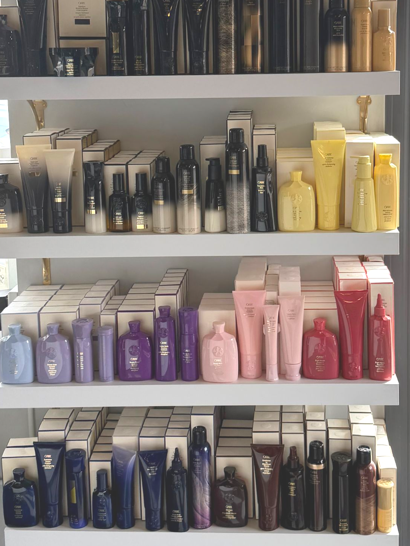 Shelves displaying an assortment of colorful hair care bottles and product boxes arranged by color gradient.