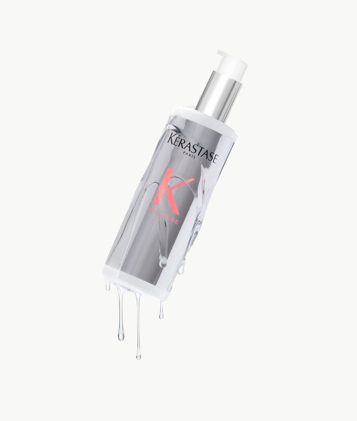 A Kérastase hair care bottle angled against a white background, with liquid dripping down its sides.
