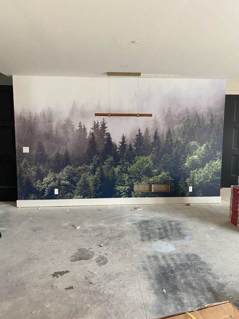 A room with a picture of a forest on the wall.