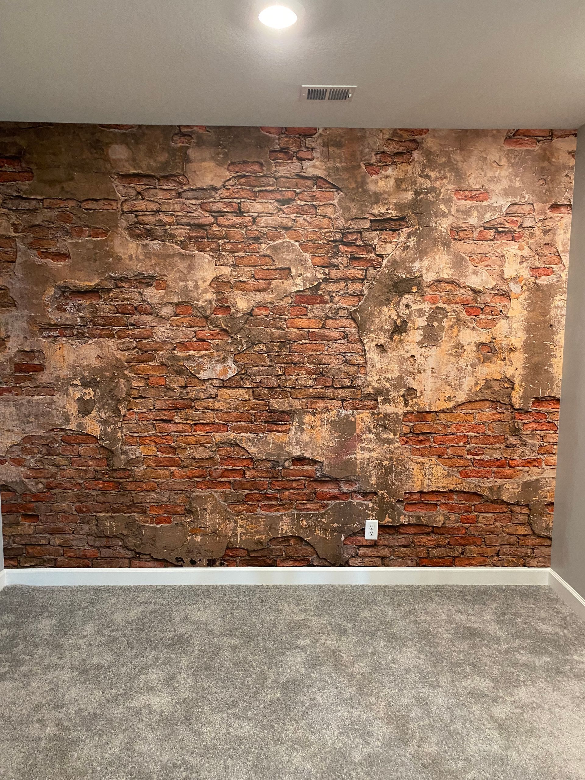 A person is using a spatula to remove wallpaper from a wall.